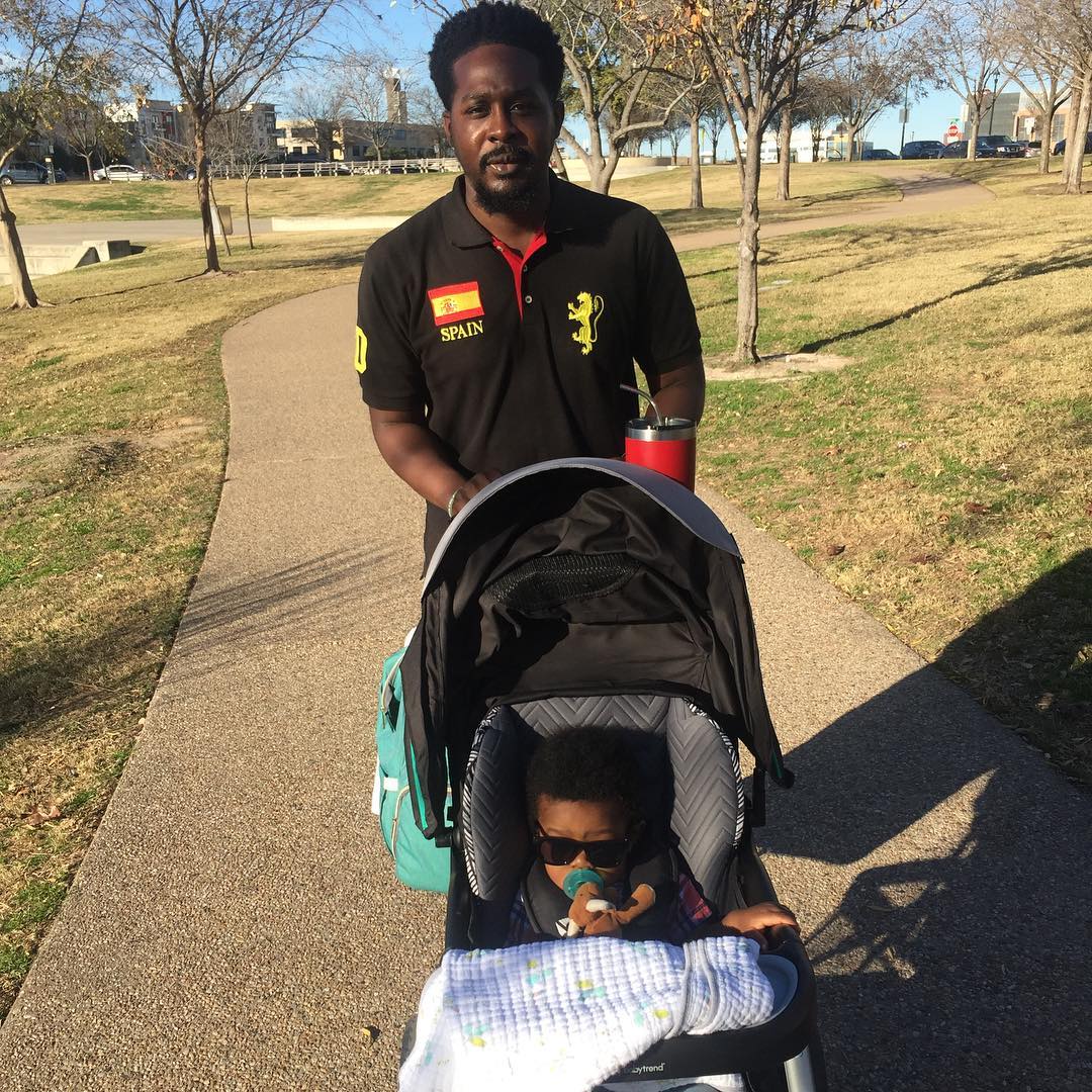 Father walking through a park while pushing his son in a stroller