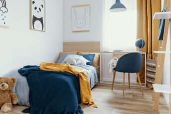 A kids room with a twin-size bed, a desk, and a bookcase. The color theme is navy and mustard with animals.