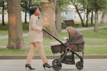 A woman wearing professional attire and high heels while pushing a stroller outside. She is talking on a cell phone.