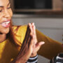 A Black mother and her daughter sitting on the front steps at home high-fiving each other with smiles on their faces.