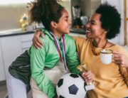 Proud Black mother feel so excited to see her daughter medal and trophy in her hand after her soccer game.