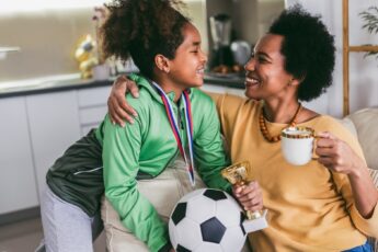 Proud Black mother feel so excited to see her daughter medal and trophy in her hand after her soccer game.