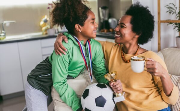 Proud Black mother feel so excited to see her daughter medal and trophy in her hand after her soccer game.