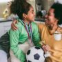 Proud Black mother feel so excited to see her daughter medal and trophy in her hand after her soccer game.