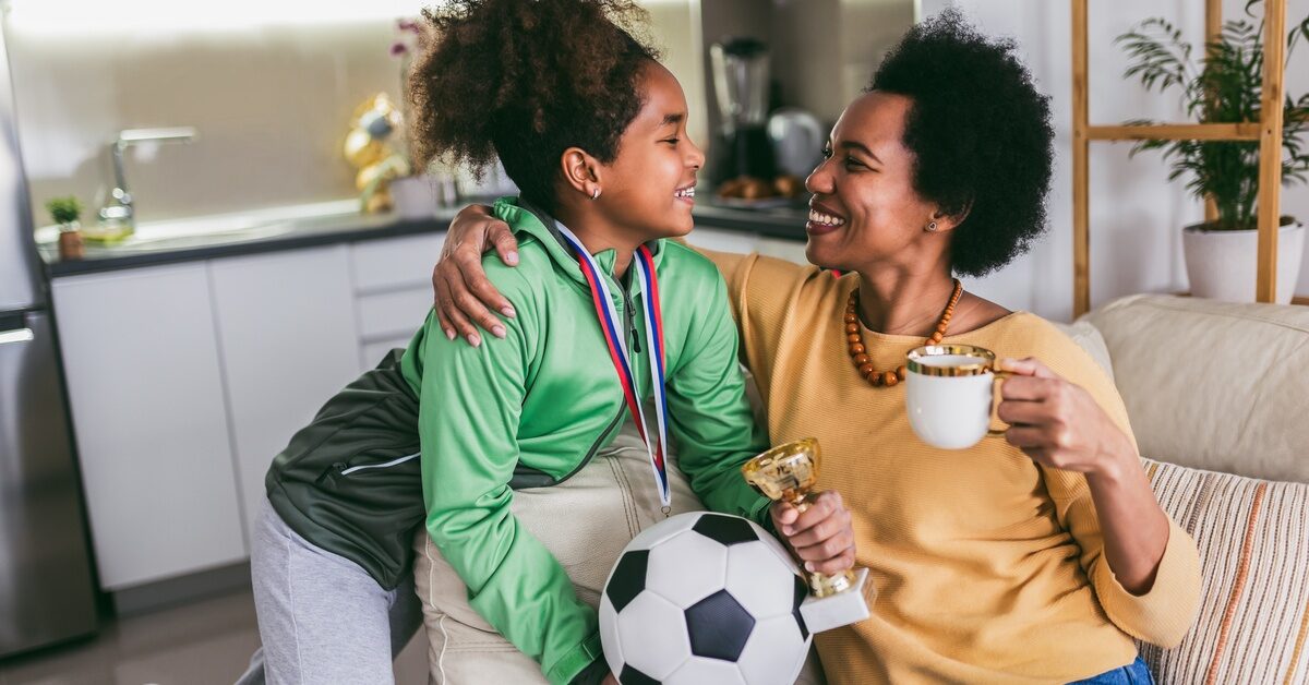 Proud Black mother feel so excited to see her daughter medal and trophy in her hand after her soccer game.
